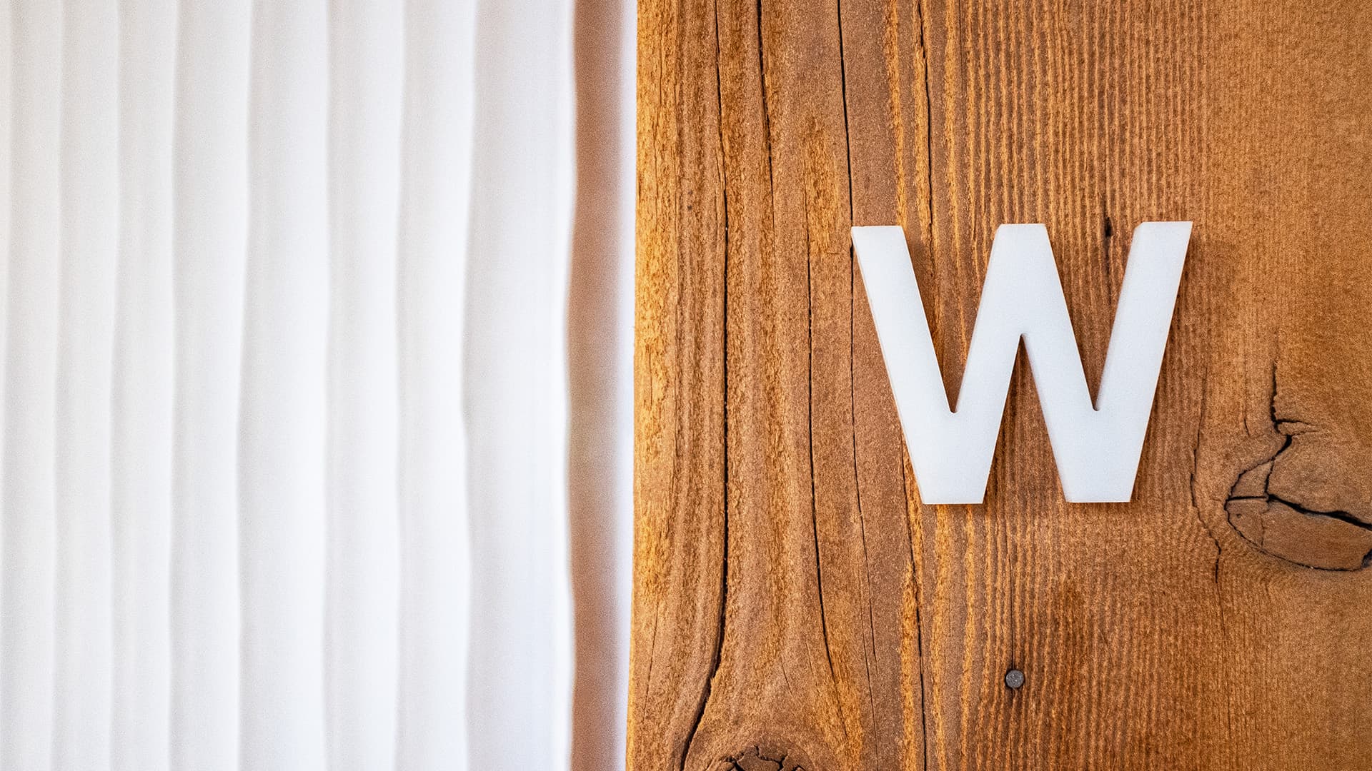 Close-up of a plastic letter “W” mounted on a wooden beam at the Works Design office.