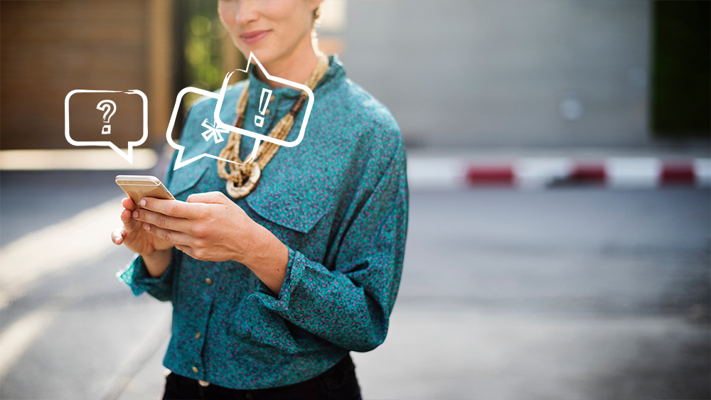 Speech bubbles emerge from a smartphone held by a woman.