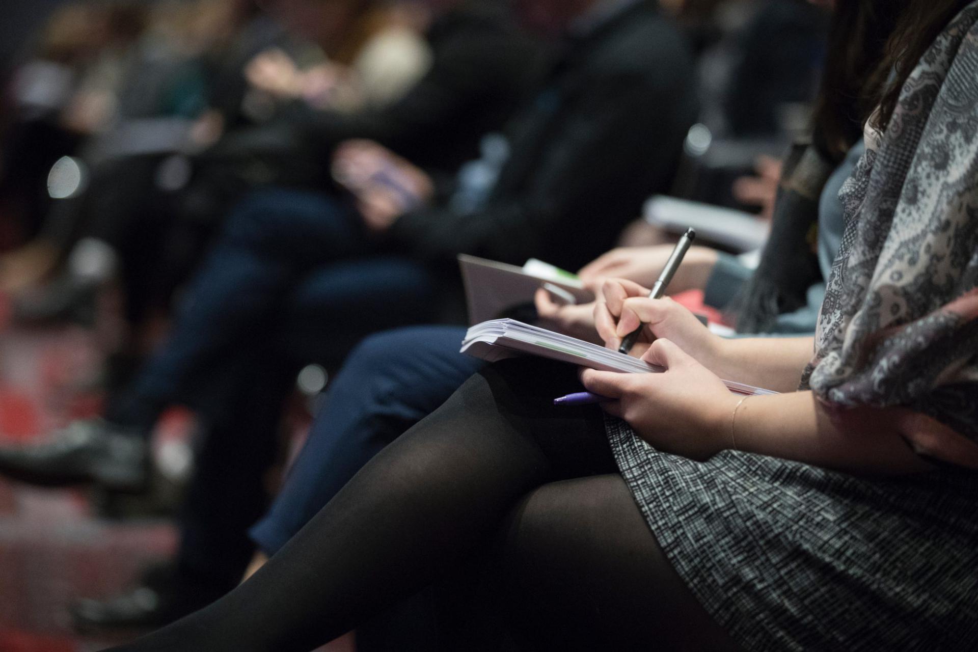 Attendees take notes at a conference.