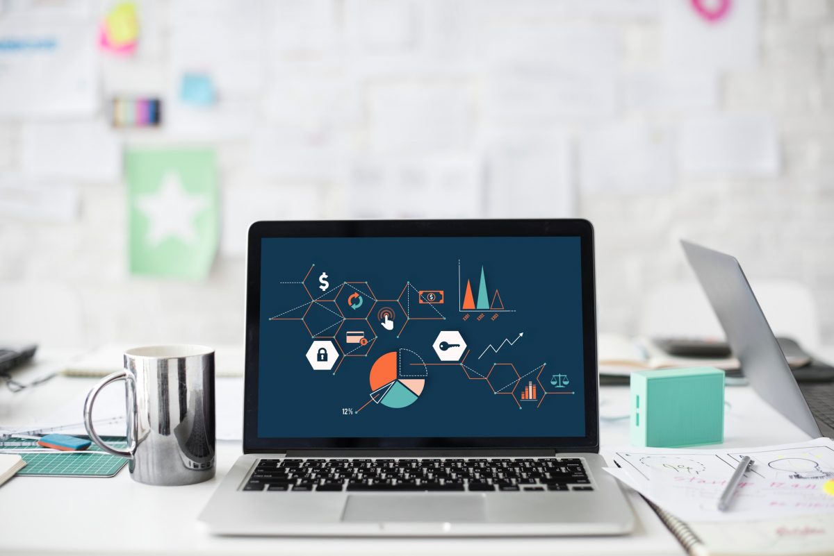 A laptop on a desk displaying various charts and graphs.