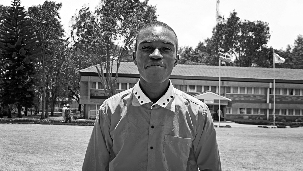 A young man stands outside a school in Kenya.