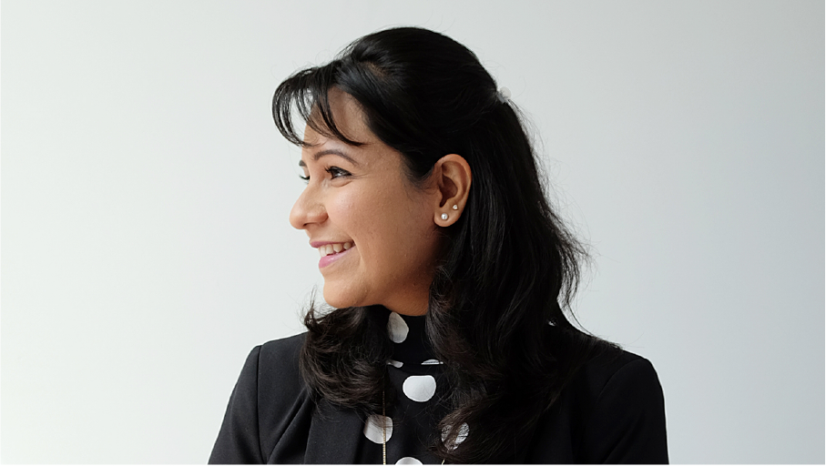 A woman is smiling in a polka-dot shirt.