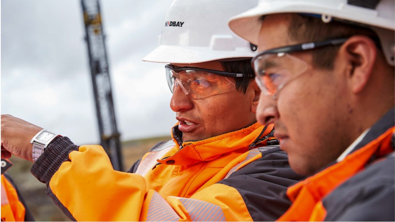 Photo of two Hudbay workers in protective gear in conversation.