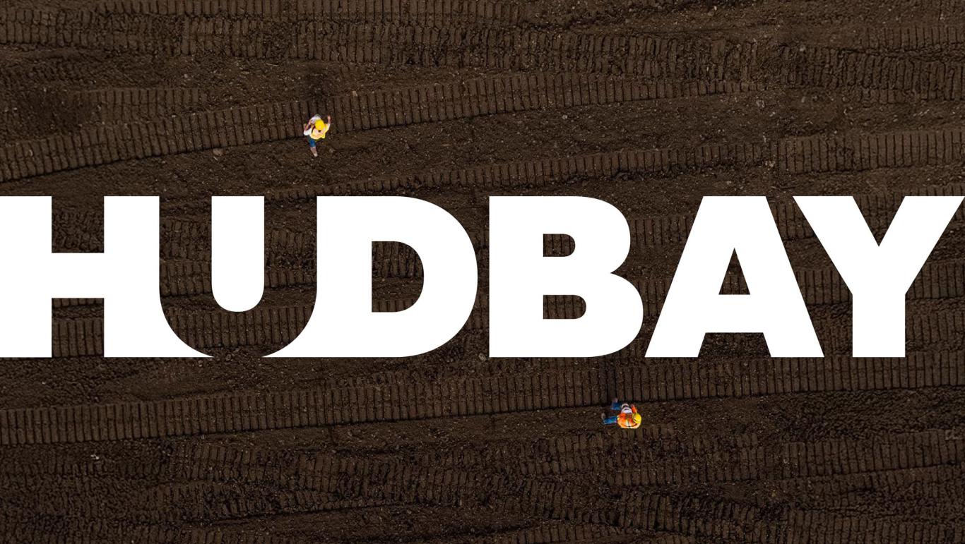 Overhead view of the Hudbay logo superimposed on top of dark soil with tire tracks.