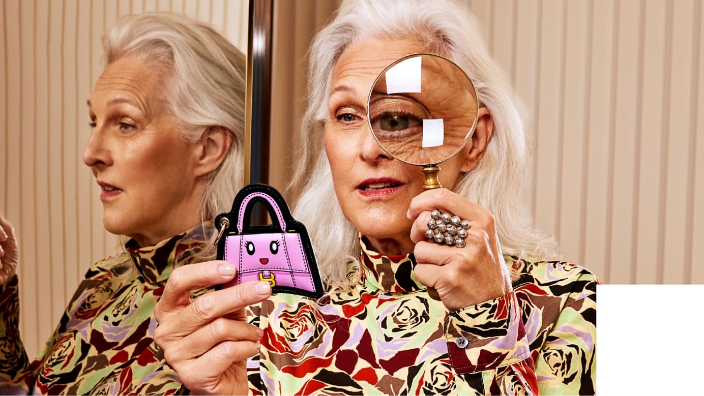 Image from Holt Renfrew’s 2024 Sustainability Report of an older woman using a magnifying glass to look at a keychain.