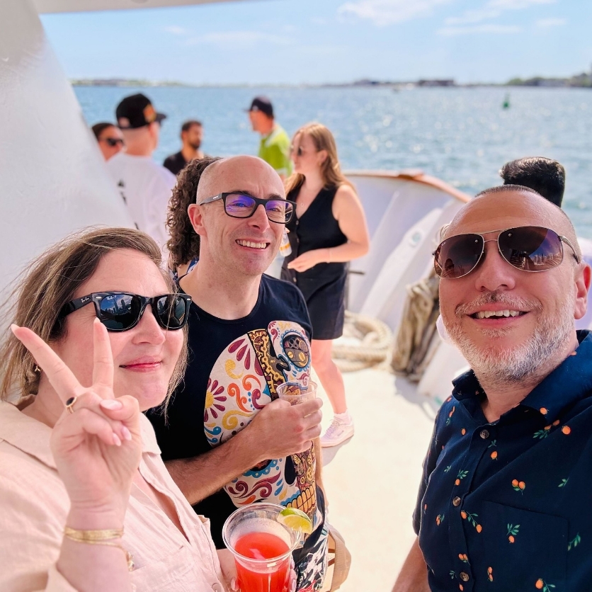 Three Works Design colleagues pose for a selfie on a boat at a social gathering.