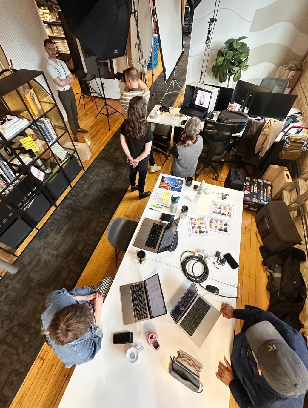 A photographer takes pictures of a Works Design team member as colleagues look on in the Works Design office.