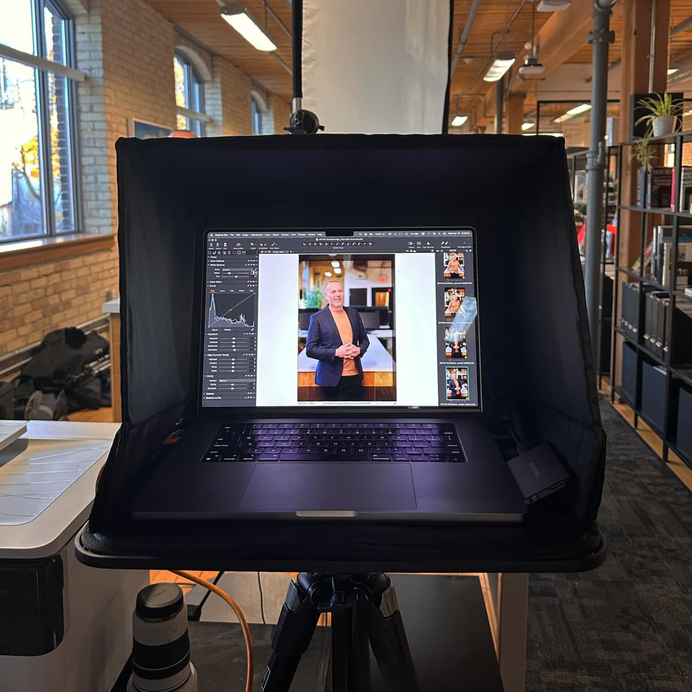 An open laptop in the Works Design office shows a photo onscreen in an image editing program.